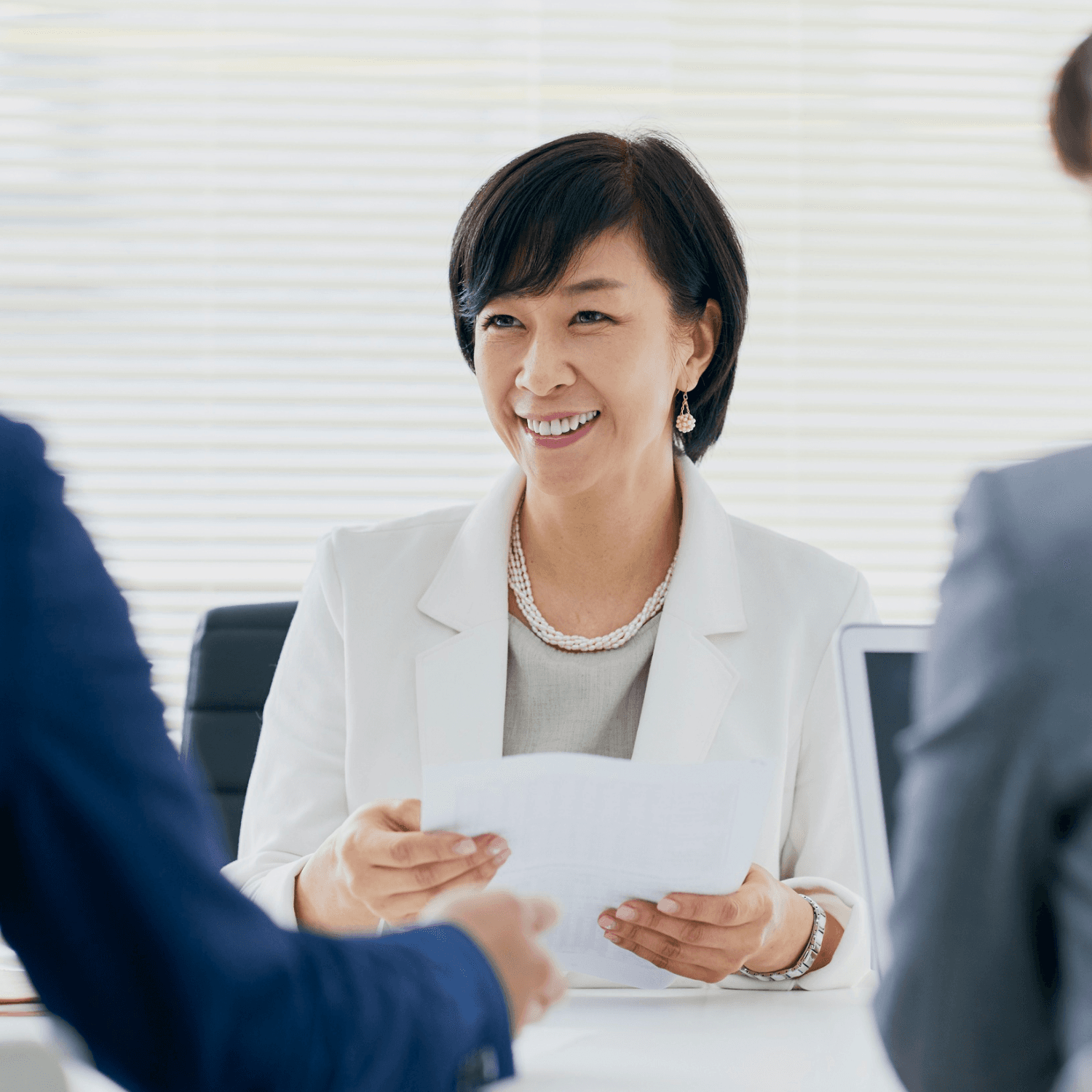 A DEX account manager reviewing a printed document with two clients across a meeting table