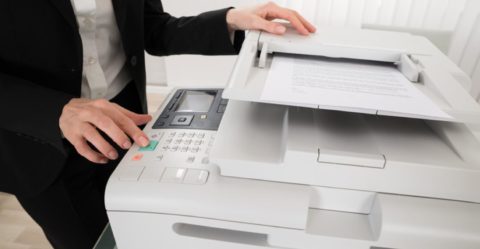 Person hitting start button on copier