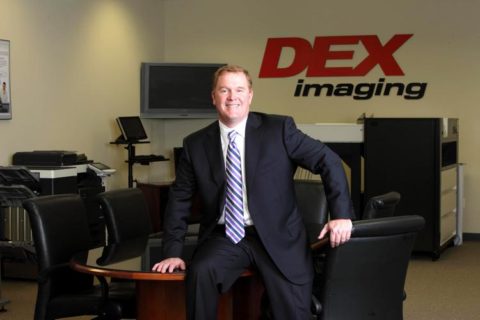 Dan Doyle Jr. sitting on edge of conference room table