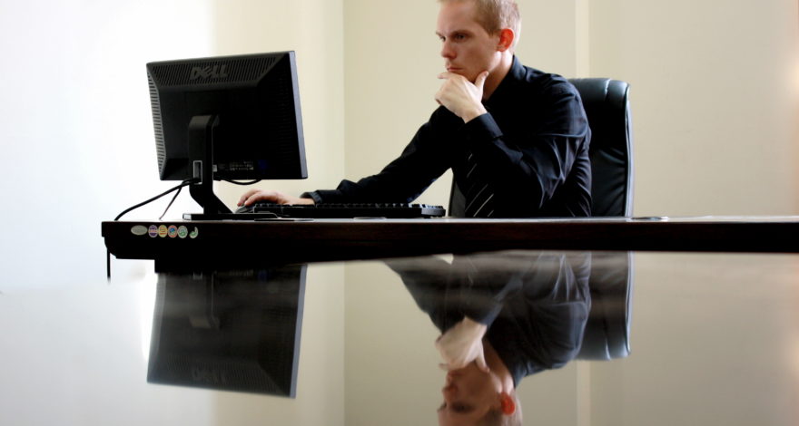 stock photo: man at desk staring intensely at computer monitor