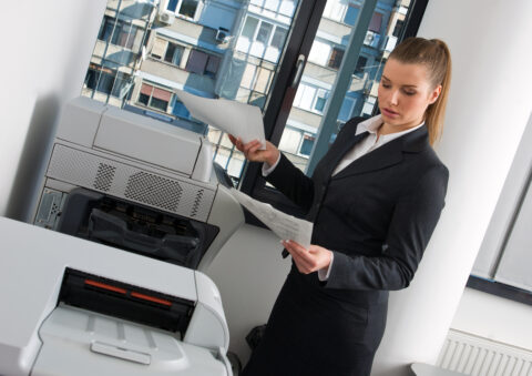 business woman with documents standing next to printer