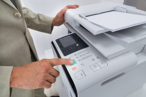 Midsection side view of businessman pressing printer's button in office