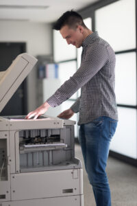 young business man copy documents on copy machine at modern startup office interior, casual clothes