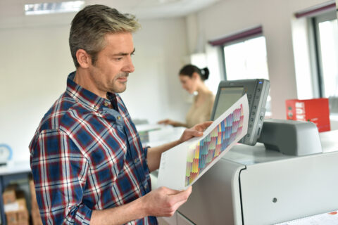 Man working in printing house, programming printer machine
