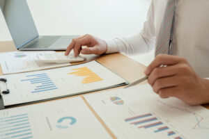 A business man is sitting at a desk and calculating financial graphs about real estate investment expenditures.