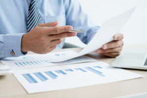 The businessman's hand sits at their desks and calculates financial graphs showing results about their investments, plan a successful business growth process.