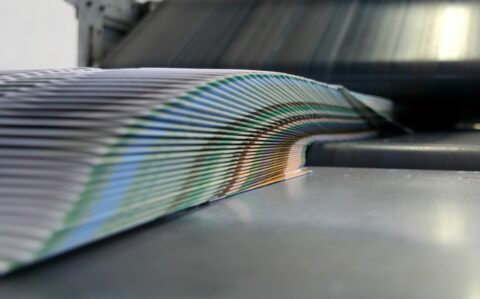 Stack of folded booklets emerging from a printer.