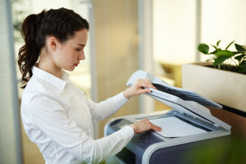 Young office worker making photocopies on copier in office