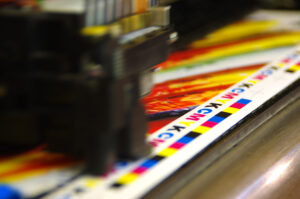 Printing head creates CMYK test and image on paper. Colorful large plotter printer machine.