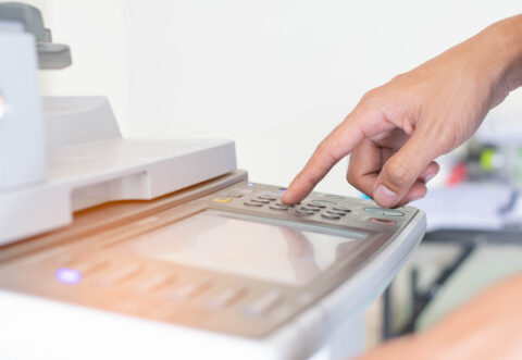 a man is pressing a button of printer’s control panel