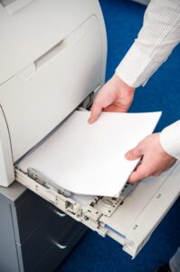 Office worker adds paper to the paper tray in a laser printer