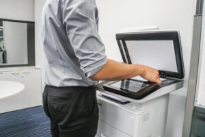 businessman presses paper sheet on printer for copying and scanning documents