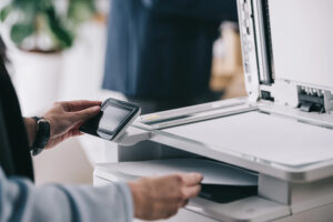 Closeup of office worker using a photocopier, removing a copy from a lower tray.