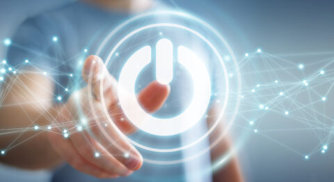 Businessman on blurred background using power button with electronic connections