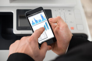 Cropped image of businessman giving print command on smart phone in office