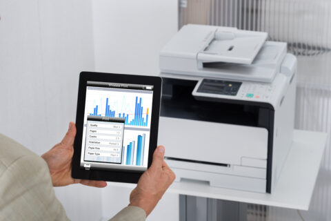 Cropped image of businessman giving print command on digital tablet in office