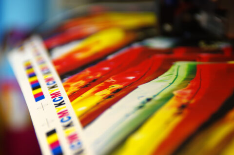 Printing CMYK mark on white paper. Large digital printer machine in printing house.