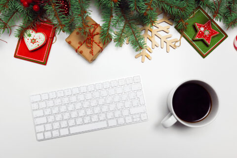 Closeup of desk with computer keyboards and coffee cup, along with Christmas decorations