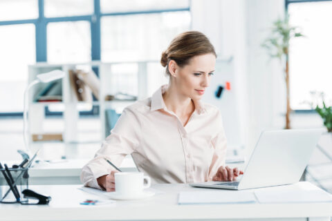 Office manager working at her desk with laptop and coffee mug