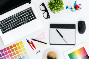 Designer's desk with laptop, glasses, pen tablet and color samples