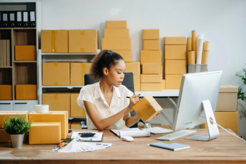 Female business owner working at a desk labeling a package