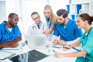 Group of healthcare professionals collaborating around a laptop