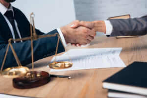 Selective focus of businessman and businesswoman shaking hands near scales in office