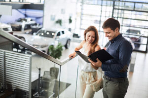 Couple at car dealership, looking at booklet together