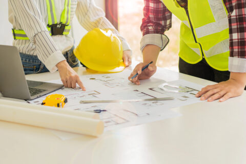 Closeup of construction documents on work table with two people pointing to them
