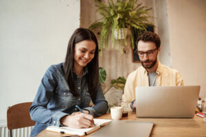 Two workers at table working on laptop