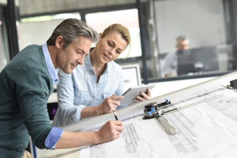 Two people working at a drafting table together at a design firm