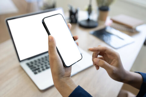 Man hand typing text message, chatting online on his mobile phone. over shoulder view.