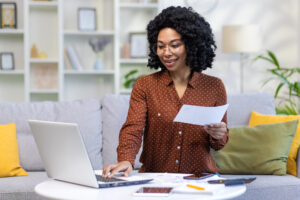 Smiling young woman working remotely at home with documents.