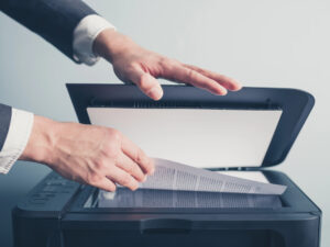 Closeup of hand placing a page on a scanner bed of an office copier