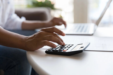 Closeup of worker's hands using a calculator and laptop
