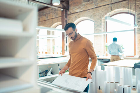 Architect removing blueprint from a wide format printer in large design studio