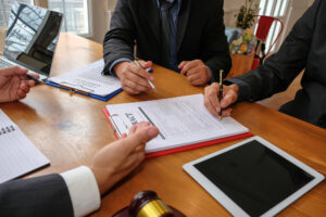 Businessman consulting lawyer and signing contract agreement at conference table.