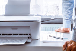 Closeup of man looking at and waiting for a desktop printer to finish printing