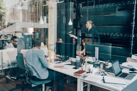 Group of office workers collaborating in glass-walled office