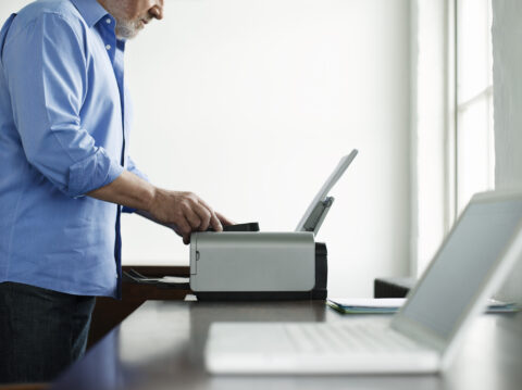 Man Using Computer Printer on Desk
