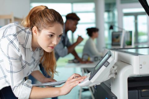 Woman putting set of ink into plotter in printing office