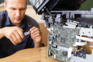 A male handyman inspects a printer before starting repairs