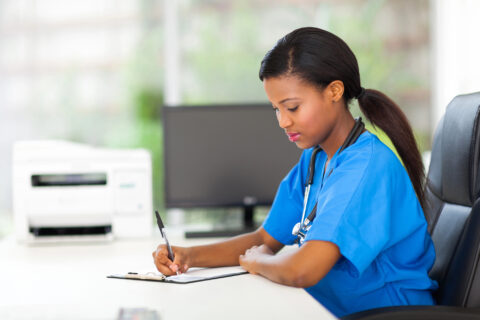 Pediatric nurse completing paperwork at desk