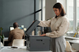 Young woman using copier in large office