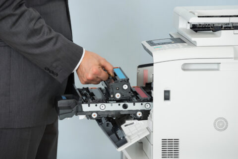 Businessman changing toner cartridge in office multifunction printer