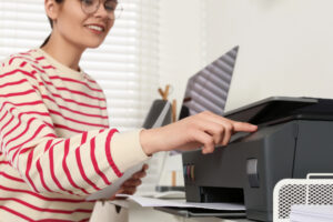 Woman pressing button on an office multifunction printer